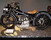 A shiny black Art Deco motorcycle of 1923 with a BMW logo on the gas tank and a boxer twin engine.