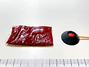 A 15&nbsp;ml packet of fake blood next to a 0.5 grain squib with a solid polycarbonate backing/shield.