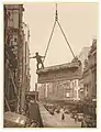 Building labourer on a stone being hoisted up to building, Pitt St, Sydney, c. 1930s. Photo by Sam Hood.