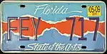This plate says "Florida" on the top, "State of the Arts" at the bottom, and incorporates a colored design that is teal on the top, blue on the bottom, and red in the middle.
