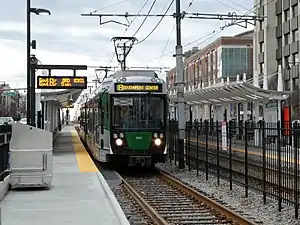 A light rail train at a surface station in the median of an urban street