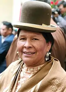Martha Yujra in traditional chola dress, including a pollera and a bowler hat.