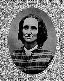 portrait of white woman with brown shoulder-length hair, wearing a plaid outfit in an oval frame