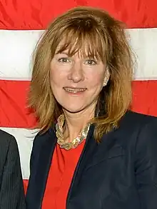 A photo of Mary-Dulany James standing in front of the U.S. flag