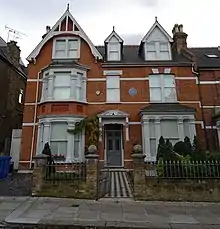 A large orange brick house with white windows and ornamentation