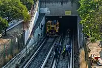 Several workers stand in front of the tunnel entrance.