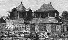 Two rectangular stone tombs, each topped with a small decorative wooden house