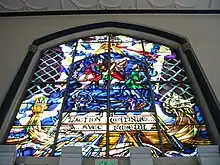 The Battle of Hastings (1066) as depicted on a stained glass window over the main entrance. The French phrase (l'action continue&nbsp;... avec fureur) translates to "the battle rages on".