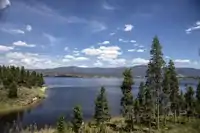 Lake with mountains in background and tall trees in foreground